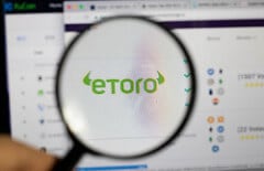 Lupe über dem Etoro-Logo auf dem Bildschirm by marcoverch etoro photo