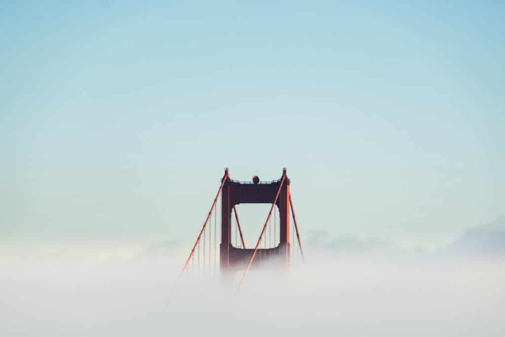 red concrete bridge surrounded by clouds